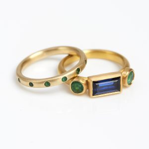18 carat gold ring with round profile, gypsy-set with tiny emeralds; 22 carat gold ring set with a sapphire and emeralds 18 carat gold ring with round profile, gypsy-set with tiny emeralds; 22 carat gold ring set with a sapphire and emeralds